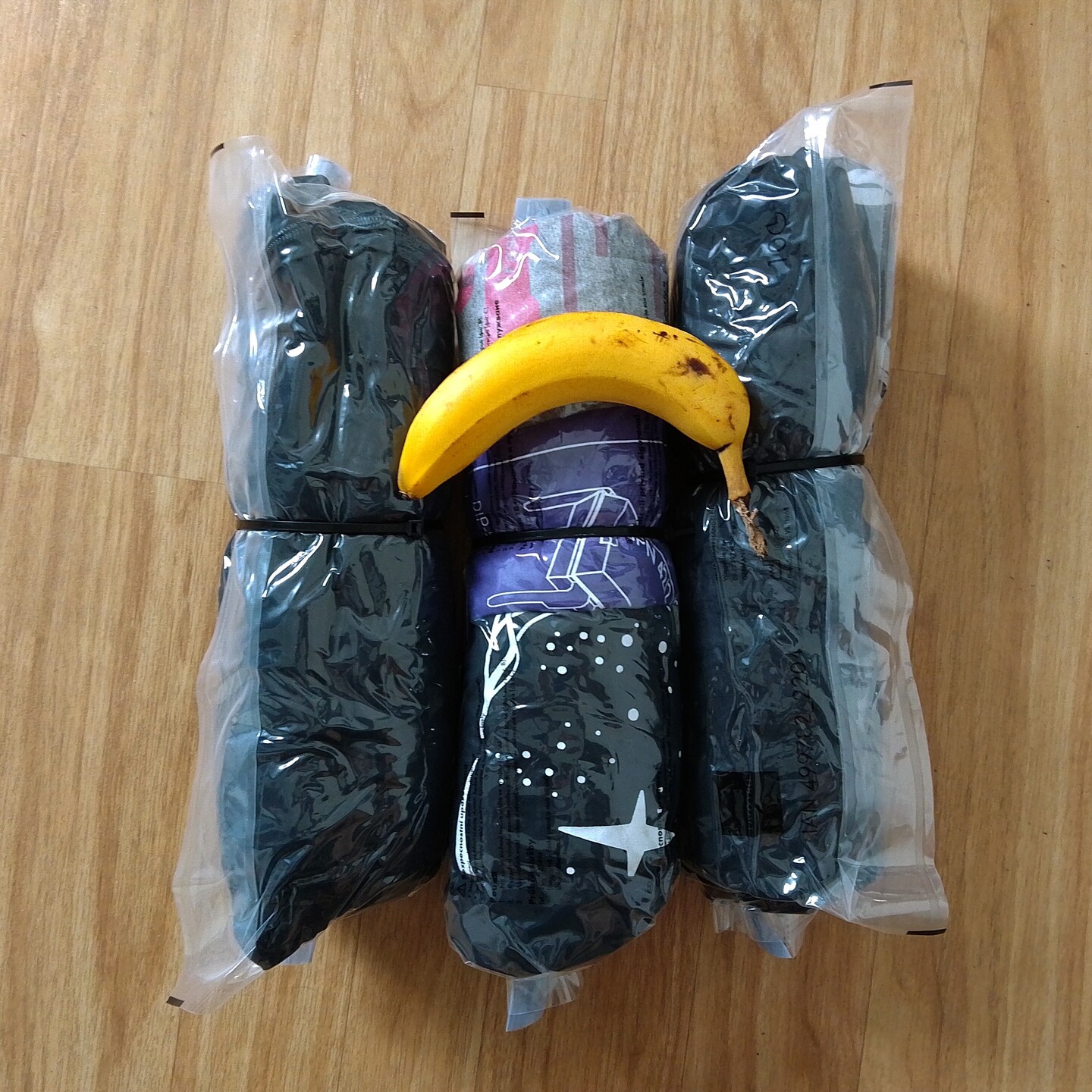 Kleidung in Vakuumbeutel eingerolt auf dennen eine Banane zum Größenvergleich liegt.